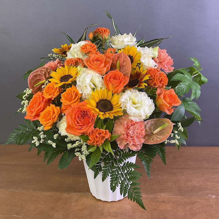 オレンジや白色の花、ひまわりなどをあしらったお見舞いのフラワーアレンジメント