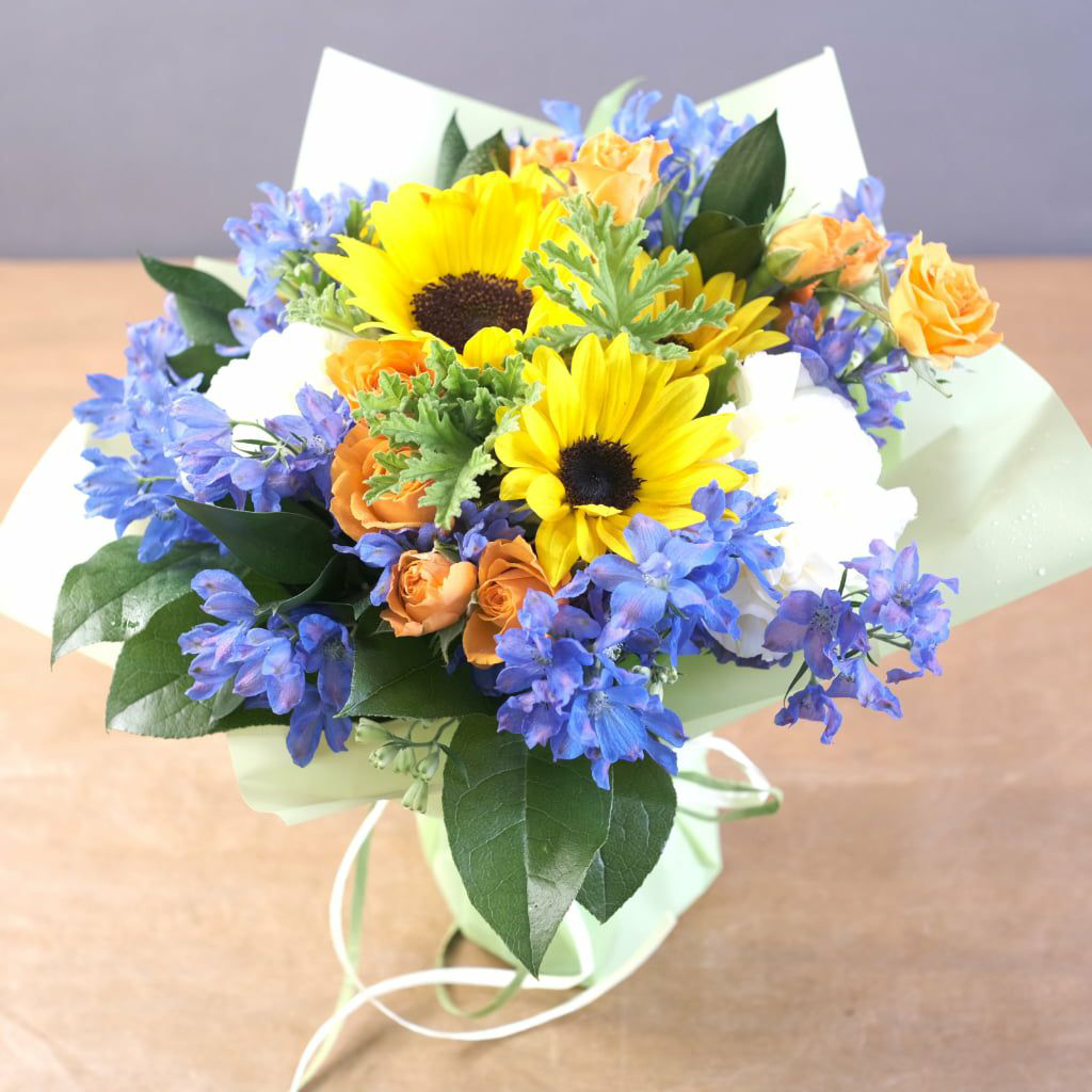 ひまわりと青い花が入った明るく爽やかさを感じさせる花束。お祝いだけでなく初盆や新盆のお供え花としてもおすすめです。